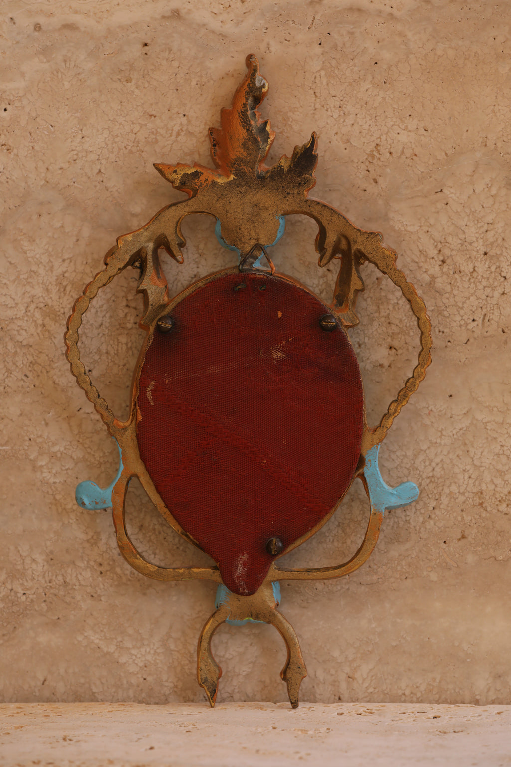 Back view of antique Italian brass portrait frame showing original red velvet backing and patina