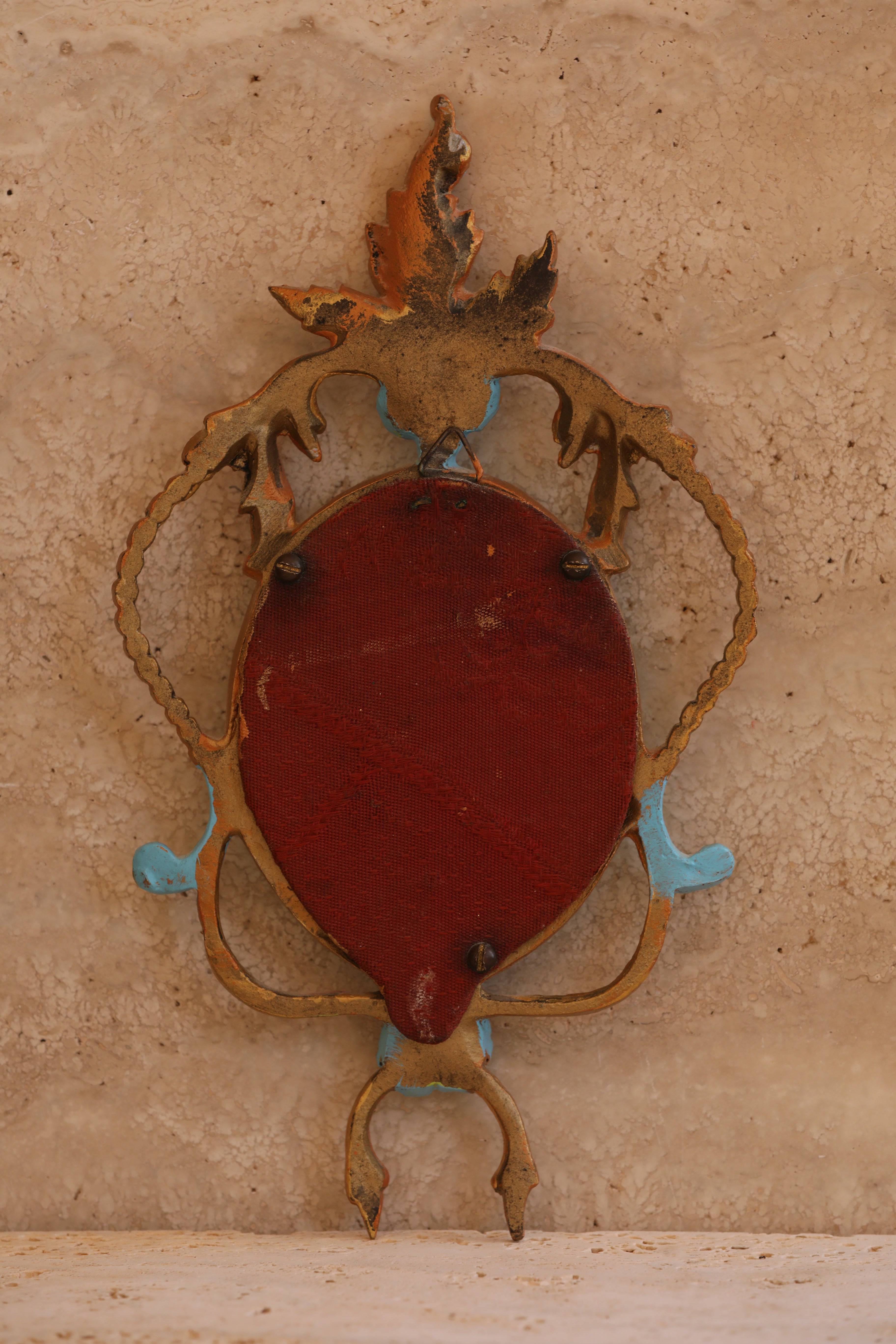 Back view of antique Italian brass portrait frame showing original red velvet backing and patina