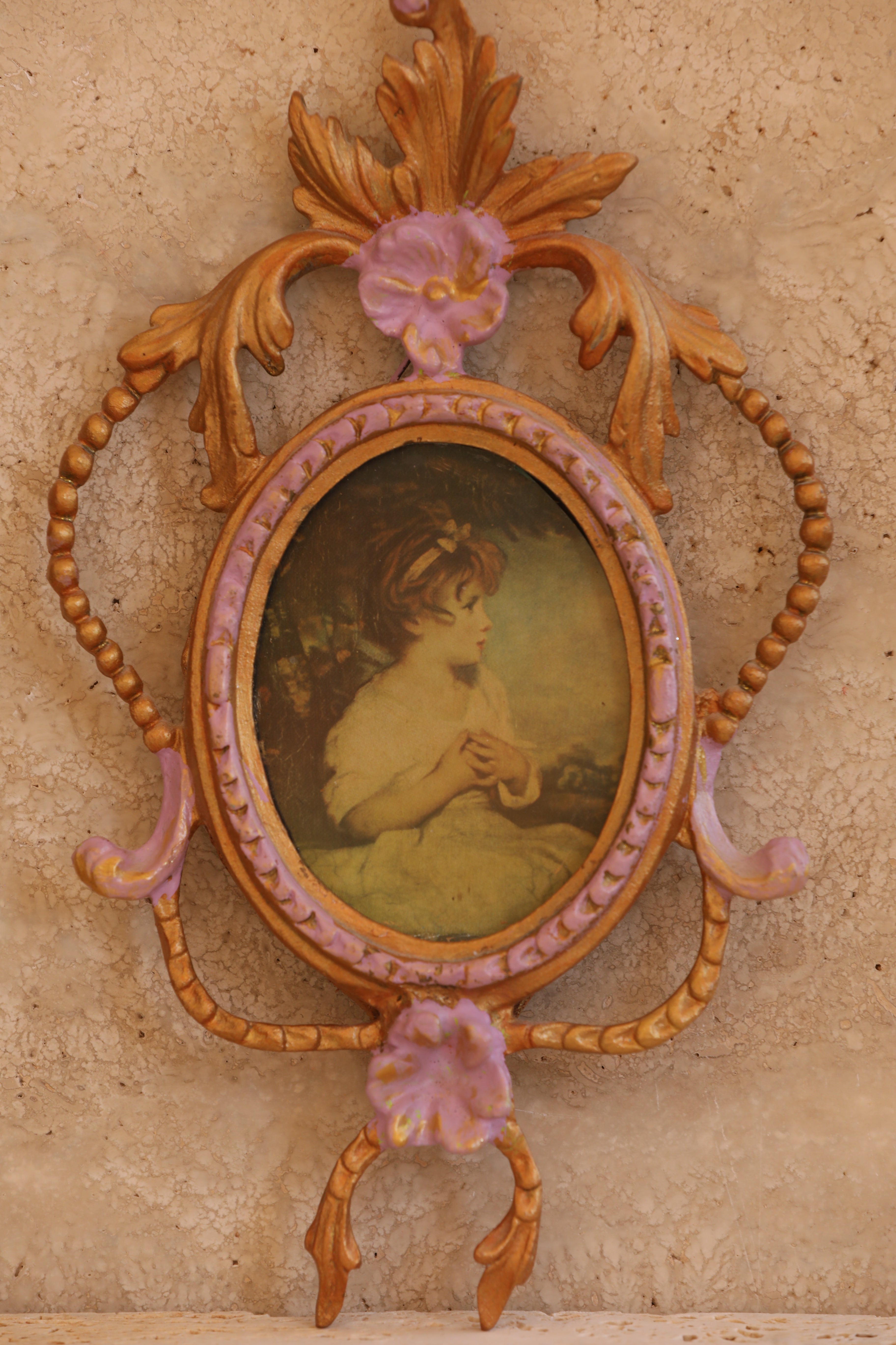 Close-up of vintage Italian brass frame with lavender floral detailing and oval portrait under convex glass