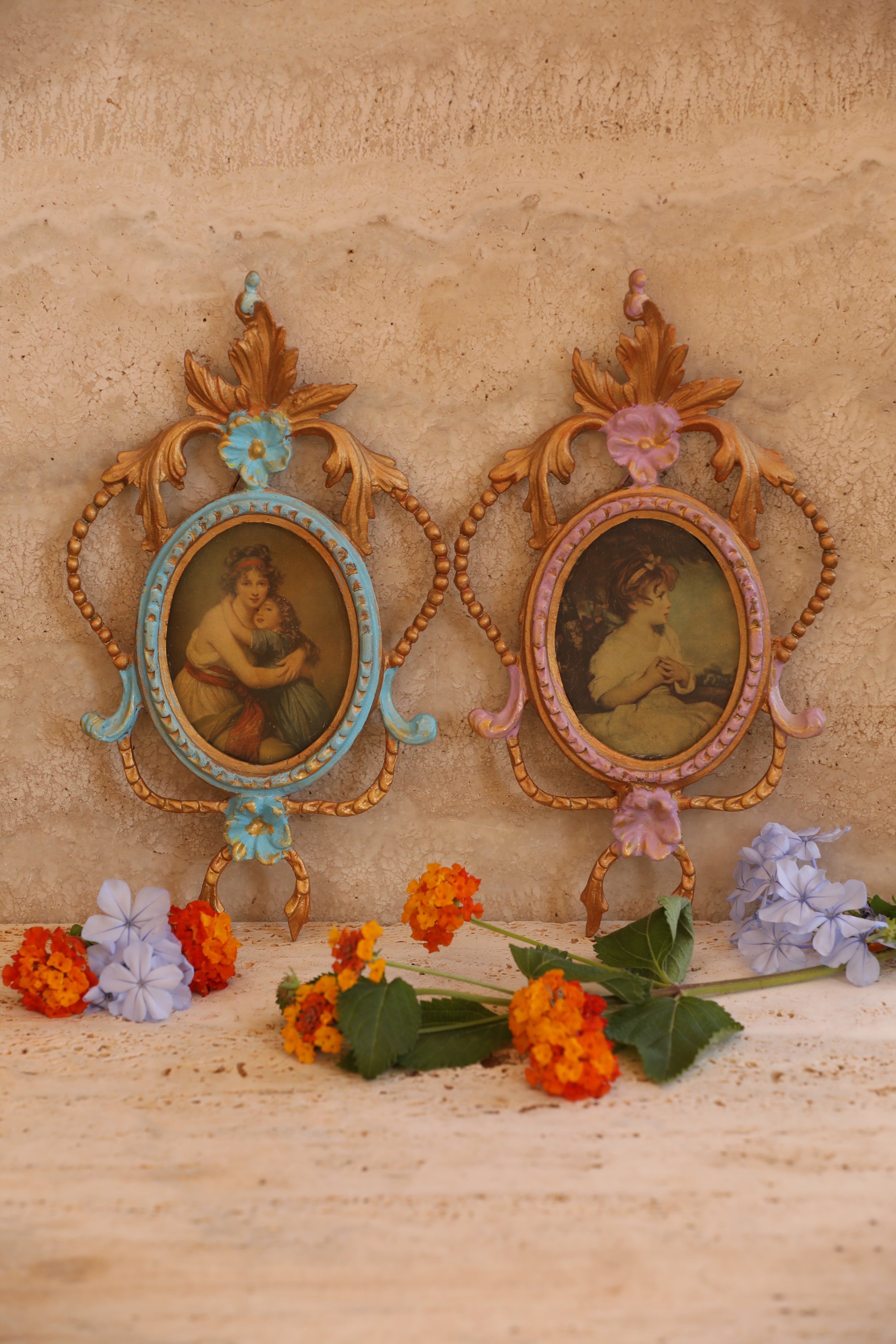 Vintage Italian brass baroque frames with painted portraits styled on travertine background with flowers