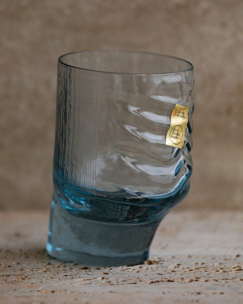 Close-up of cobalt blue sculpted tumbler glass showing textured wave design and original Arnolfo di Cambio label.