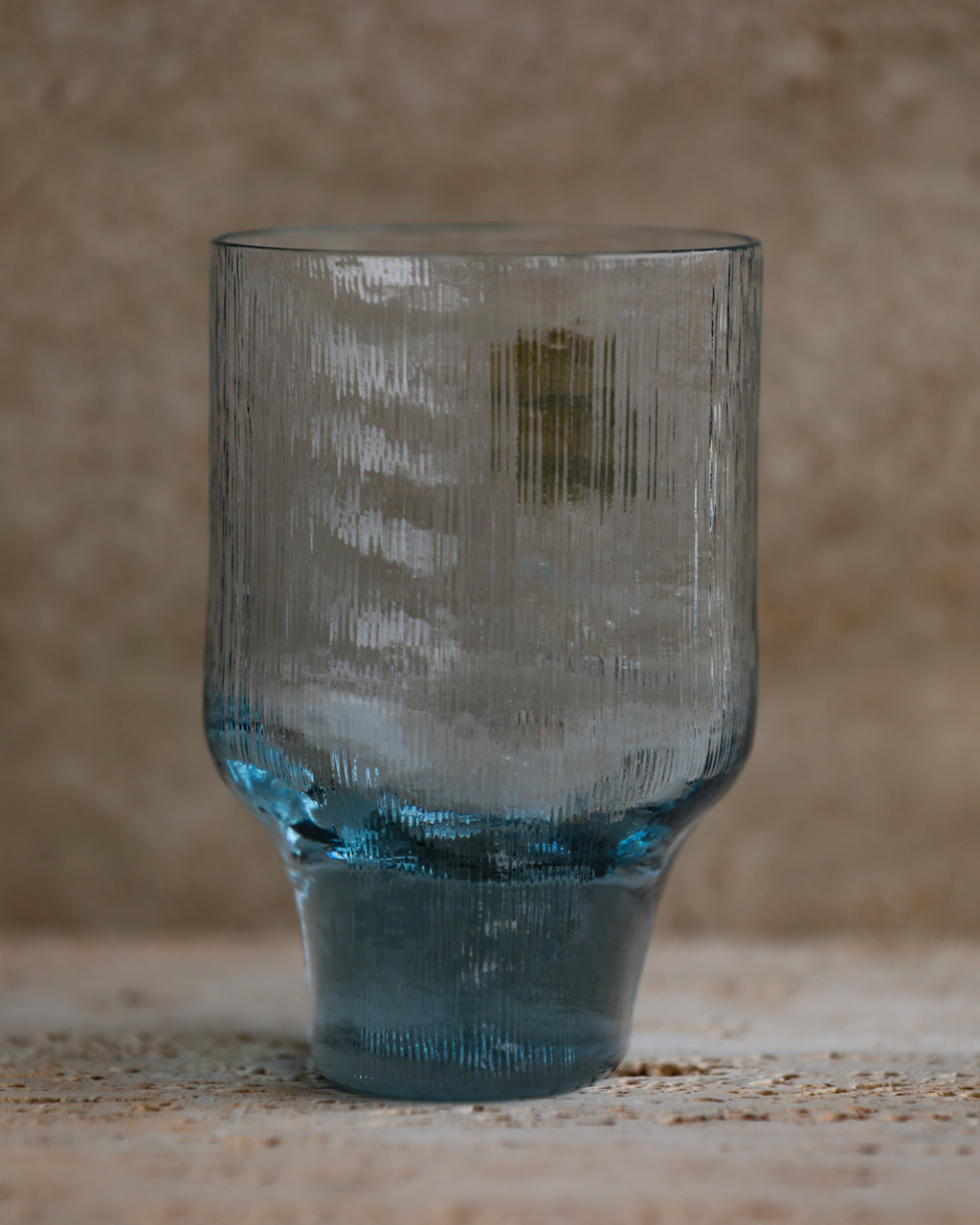 Ribbed cobalt blue tumbler glass with flared base and vertical texture.