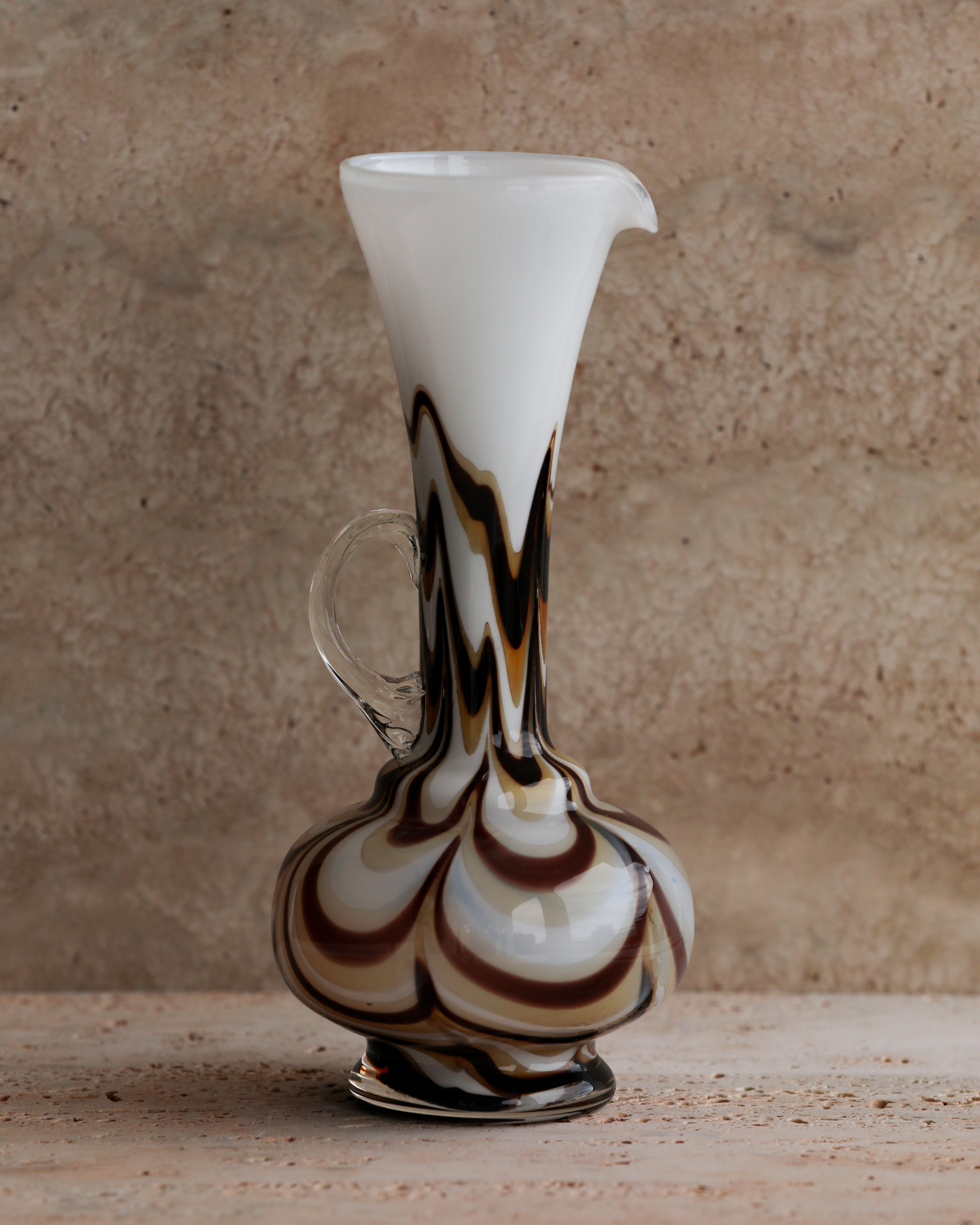 Vintage Carlo Moretti Murano glass pitcher with brown and cream marbled pattern against stone backdrop.
