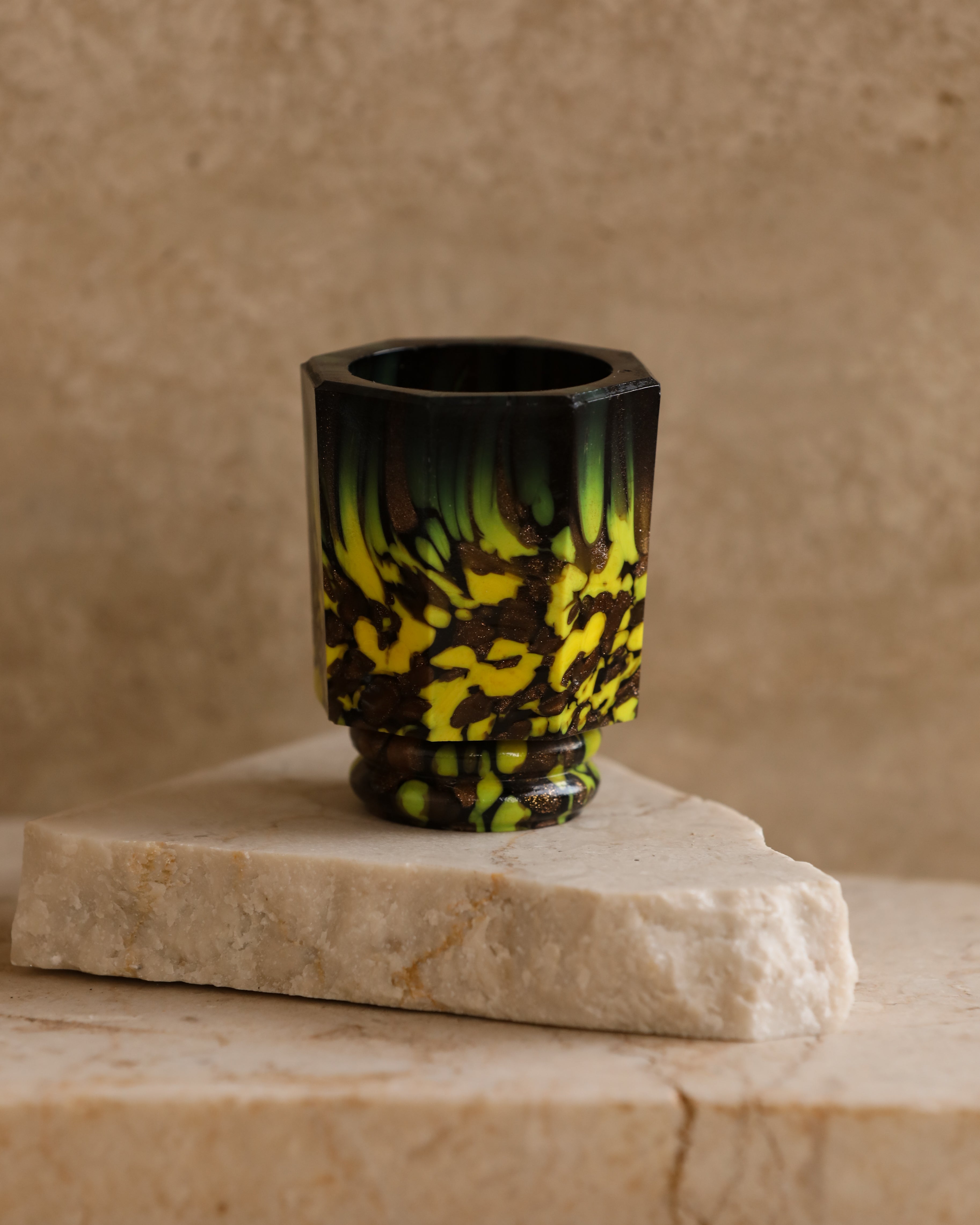 Close-up of 1970s Murano mold-blown glass shot glass with green, yellow, and amber marbling — Italian vintage barware piece